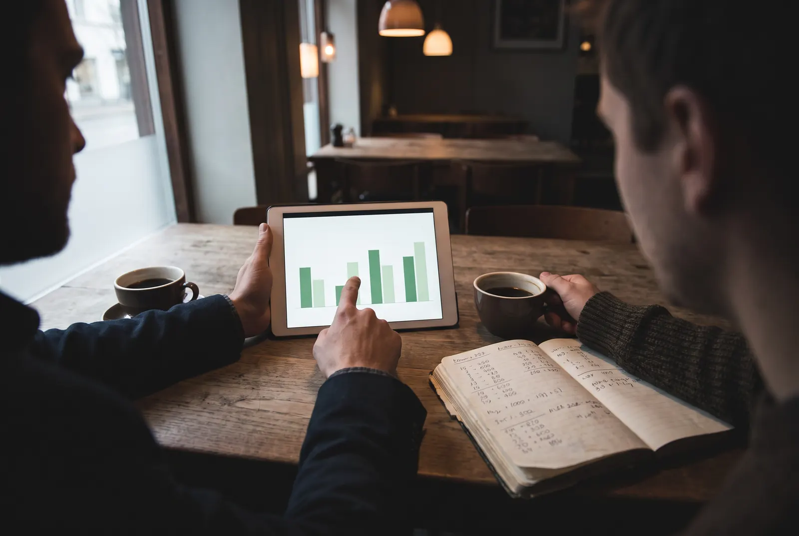 Dos personas revisando gráficos en una tablet en un restaurante